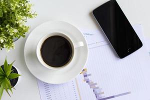 mesa de oficina, vista superior de la mesa de trabajo, mesa de trabajo con una taza de café negro foto