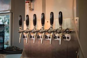 The craft beer taps at restaurant. Alcohol beverage ready to party. photo