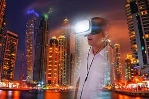 Defocus overlapping image of a man wearing virtual reality glasses and a modern building. Metaverse digital cyber technology concept. Future digital technology cyber virtual game entertainment. photo