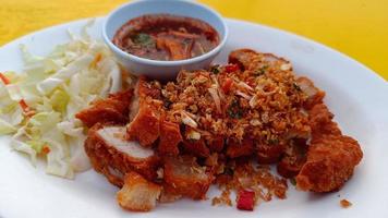 Deep fried pork belly with fish sauce on a white plate with dipping spicy sauce photo