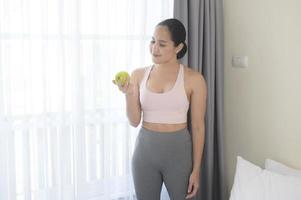 Fit young woman eating an apple after work out at home, sport and healthy lifestyle concept. photo