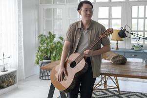 Portrait of a musician man holding guitar in home Studio photo