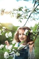 A cute little girl of 5 years old in a blooming white apple orchard in spring. Springtime, orchard, flowering, allergy, spring fragrance, tenderness, caring for nature. Portrait photo