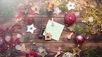 Christmas flat lay on a wooden background with keys to a new house in the center with a place for notes. New year, transfer, shares of the mortgage, the rental of a cottage. Space for text, to do list photo