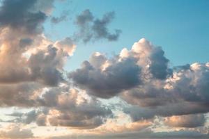 Cumulus clouds in the sky at sunset in summer illuminated by the orange light of the sun. Heavenly magic light. photo