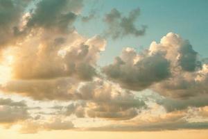 Cumulus clouds in the sky at sunset in summer illuminated by the orange light of the sun. Heavenly magic light. photo