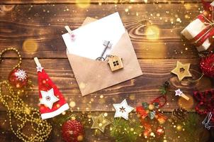 Christmas flat lay on a wooden background with keys to new house in the center with a envelope with a note sheet. New year, transfer, shares of the mortgage, the rental of a cottage. Space for text photo