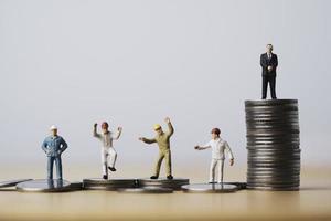 One businessman standing on highest coins stacking and many workers standing on lower coin for different income and unequal in society concept. photo