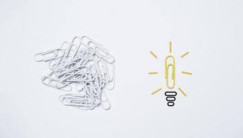 Yellow paper clip move out from white clip and transform itself to lightbulb for creative thinking idea concept. photo