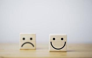 Focus of Smile face and defocus of sad face on wooden block cube for positive mindset selection concept.