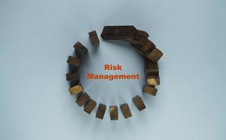 forma de círculo de dominó de madera cayendo sobre fondo azul para el concepto de gestión de riesgos. foto