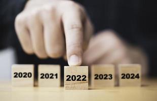 empresario empujando a mano el año 2022 que imprime la pantalla en un bloque de cubo de madera para preparar el año nuevo y comenzar un nuevo concepto de negocio. foto