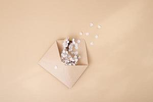 Kraft envelope with a spring twig and white spring flowers on a beige background photo