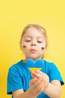 The girl holds a heart of yellow and blue color of the Ukrainian flag photo
