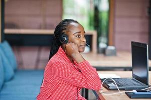 African american woman works in a call center operator and customer service agent wearing microphone headsets working on laptop. photo
