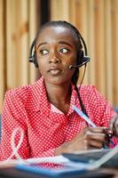 African american woman works in a call center operator and customer service agent wearing microphone headsets working on laptop. photo