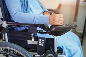 Asian elderly woman disability patient sitting on electric wheelchair in park, medical concept. photo