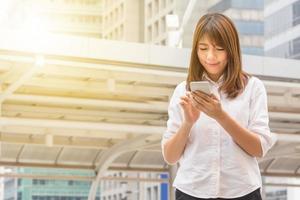 Portrait of beautiful casual businesswoman using smartphone in the city background. photo