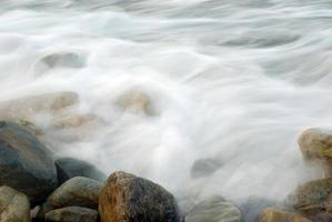 turbulencia de agua de mar y rocas en la costa foto