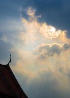 Sun beam behind the sunset clouds over the buddhist temple photo