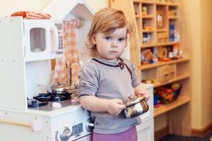 toddler girl playing toy kitchen photo