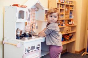 niña pequeña jugando a la cocina de juguete foto