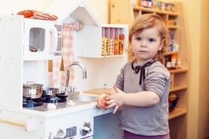 niña pequeña jugando a la cocina de juguete foto