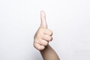 niña levantando un dedo en la mano que es el pulgar hacia arriba muestra un símbolo excelente o excelente sobre fondo blanco. foto