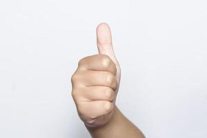 niño levantando un dedo en la mano que es el pulgar hacia arriba muestra un símbolo excelente o excelente sobre fondo blanco. foto