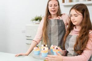 Mother and daughter preparing and decorating homemade cake photo