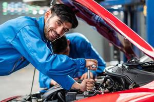 feliz sonrisa caucásico mecánico de automóviles hombre comprobando daños en el automóvil condición de la pieza rota, diagnóstico y reparación del vehículo en el garaje automotriz, mantenimiento técnico del motor después del concepto de servicio foto