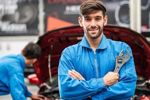 Portrait of Caucasian automotive mechanic man holding wrench. assistant worker repairing car checking auto damage in auto garage, transport business and after service concept photo