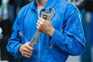 Mechanic hand holding wrench equipment tool in auto repair garage. checking car damage broken, repairing vehicle business. motor technician maintenance after service photo