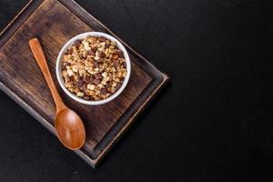 sabroso desayuno saludable con cereales, granola, chocolate, leche y mermelada sobre un fondo de hormigón oscuro foto