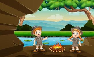 Cartoon the explorer boy and girl lit a bonfire in the cave vector