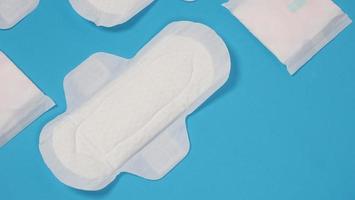 Woman sanitary napkins on blue background. Top view. photo