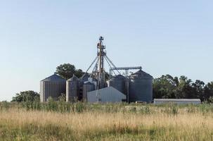 Rural silos between grass and trees photo