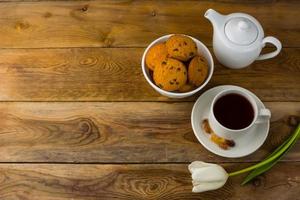 Tea cup, cookies  and teapot on wooden background, copy space photo