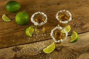 Tequila shots with lime and salt on the wooden background top view photo