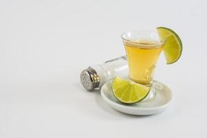 vaso de tequila con limón en el fondo blanco foto