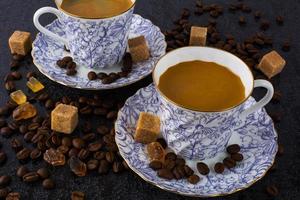 Two coffee cups and coffee beans on black background photo