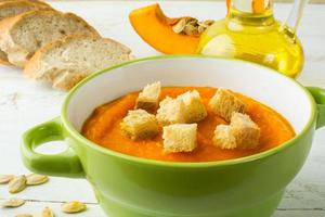 Creamy pumpkin soup with croutons in a green bowl