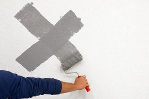 worker drew a cross with a roller on the white wall photo