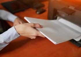 businesswoman pull pieces of paper from the printer photo