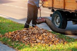 Worker clearing up the leaves using a leaf blower tool photo