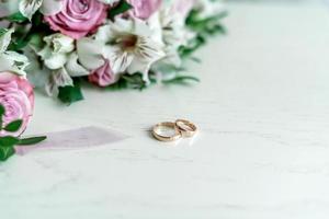wedding rings on a white background next to a bouquet. photo