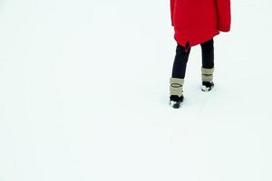 un niño caminando en la nieve en una vista trasera de chaqueta roja. foto