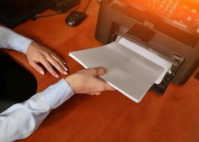 businesswoman businessman put paper sheet into printer tray photo