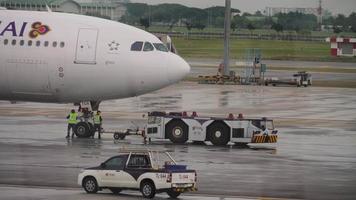 BANGKOK, THAILAND - NOVEMBER 11, 2017. Airbus A330 Thai Airways on the platform at the terminal of Suvarnabhumi Airport. Aircraft being towed by a tractor. Tourism and travel concept video