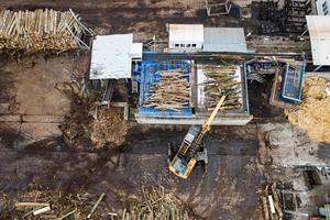 a loader loads logs at a wood processing factory from above from a drone photo
